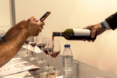 Sommelier pouring red wine for tasting while recording with smart phone