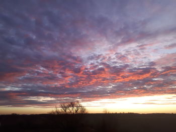 Silhouette landscape against dramatic sky during sunset