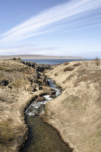 Little mountain stream flowing between rocks and grassy hills towards the fjord 