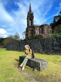 View of cross sitting on grass outside temple against building