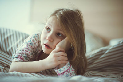 Portrait of cute girl lying on bed at home