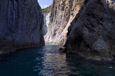 Scenic view of sea by rock formation against sky