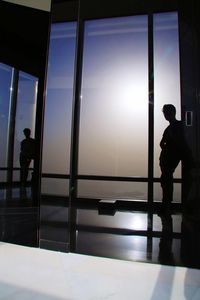 Silhouette man standing in glass window