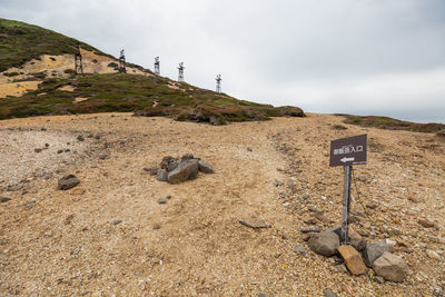 Text on rock on land against sky