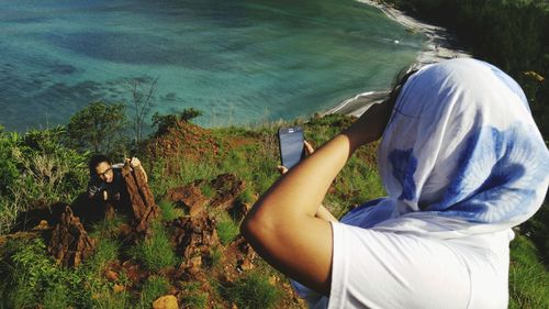 Woman photographing sea through mobile phone