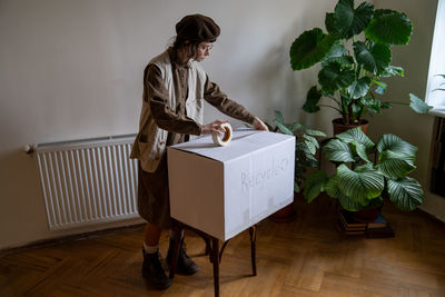 Girl lives eco friendly lifestyle collecting things for recycling packing cardboard box sticky tape.