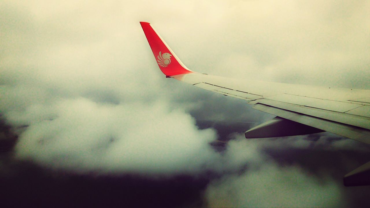 sky, low angle view, cloud - sky, airplane, air vehicle, flag, cloudy, flying, no people, weather, outdoors, cloud, overcast, day, identity, transportation, aircraft wing, dusk, part of, mode of transport