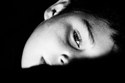 Close-up portrait of boy looking away against black background