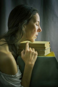 Woman in a white blouse with a carmen neckline with her hands resting on an old book