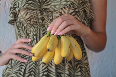 Midsection of woman holding bananas