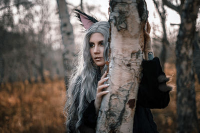 Young woman standing against tree during autumn