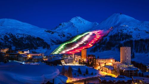 Aerial view of illuminated snowcapped mountains against blue sky at night