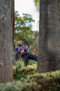 Caucasian model standing in between palm trees in a public park