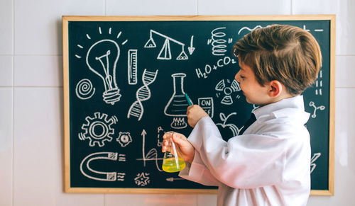 Cute boy examining chemical in classroom