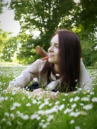 Thoughtful young woman lying on flowering field at park
