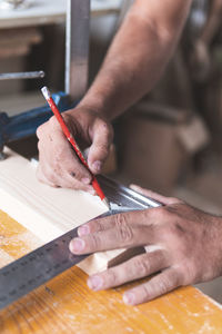 Young male carpenter marking on wood using pencil and ruler while working in workshop