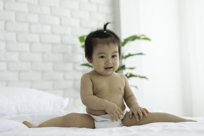 Portrait of shirtless boy lying on bed at home