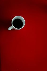 Directly above shot of coffee cup against red background