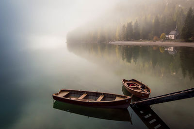 Boat moored in calm lake during foggy weather