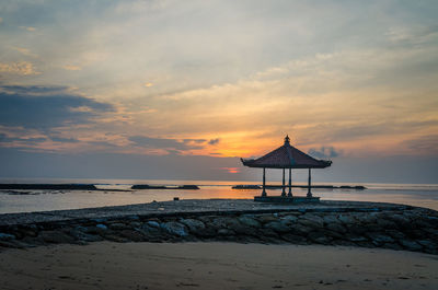 Lifeguard hut on beach against sky during sunset