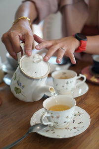 Cropped hand holding coffee on table