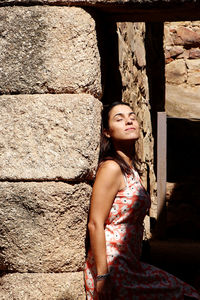 Side view of woman with eyes closed standing against wall