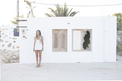 Full length of woman standing against wall