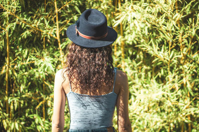 Young girl on her back with a hat on her head against bamboo leaves