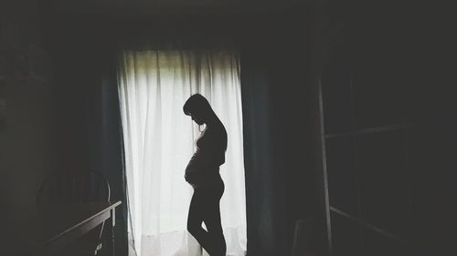 Pregnant woman standing in darkroom