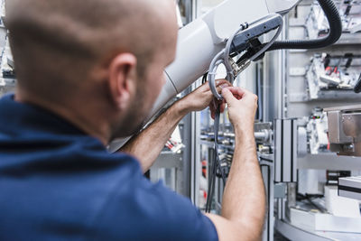 Man working at industrial robot in modern factory