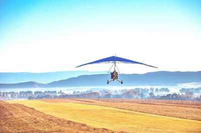 Air vehicle flying over field against sky