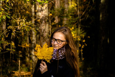 Close-up of young woman holding autumn leaves