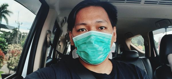 Portrait of man wearing mask sitting in car