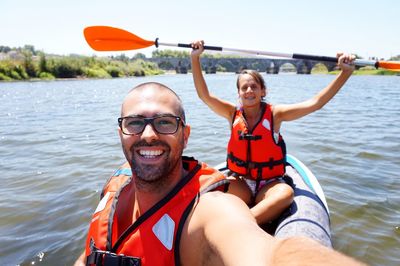 Portrait of happy young man and woman kayaking on river