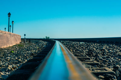 Surface level of railroad tracks against clear blue sky