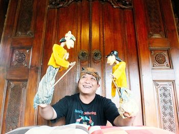 Happy young man showing puppet show against closed door