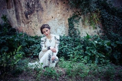 Portrait of a smiling young woman sitting in forest