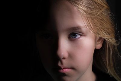 Close-up portrait of girl over black background