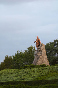 Low angle view of statue on rock against sky