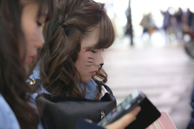 Close-up of woman using mobile phone in city
