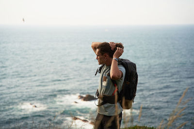 Male backpacker walking on hill during trekking in summer and looking away