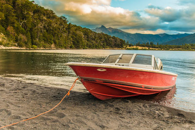 Boat moored at lakeshore against sky