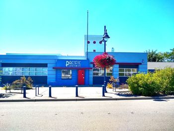 Road by building against clear blue sky