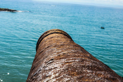 Close-up of metal container at beach against sky