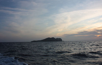 Islet or rocky cliff between the rough sea of ibiza and the blue sky in balearic islands