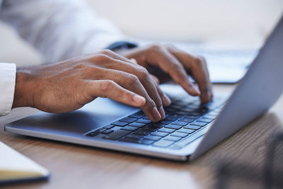 Cropped hands using laptop on table