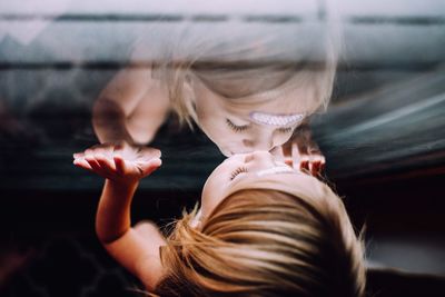High angle view of girl kissing window with reflection