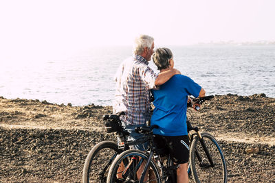 Rear view of people on beach by sea