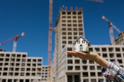 A woman's hand holds a mock-up against the background of an apartment building