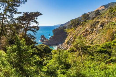 Scenic view of sea by mountains against clear sky